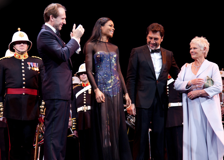 Dame Judi Dench is introduced on stage at the Royal Albert Hall alongside (L-R) Ralph Fiennes, Naomie Harris and Javier Bardem. Standing behind are musicians from Her Majestys Band of the Royal Marines Portsmouth, who earlier had performed a drum march on the red carpet, and a medley of theme tunes to mark the 50th anniversary of James Bond on film.