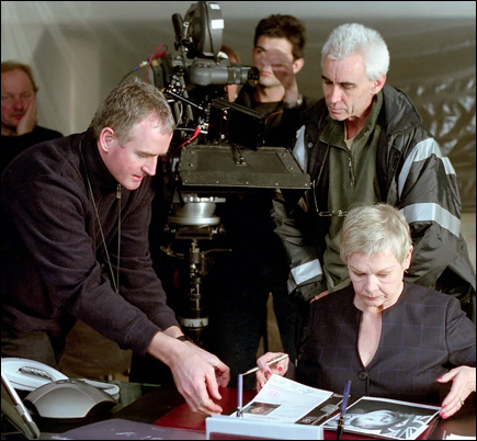 Cinematographer David Tattersall (left), adjusts a file folder for M (Judi Dench) as director Lee Tamahori observes.