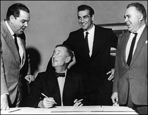 Ian Fleming signing a contract flanked by Sean Connery and James Bond producers Albert R. Broccoli & Harry Saltzman